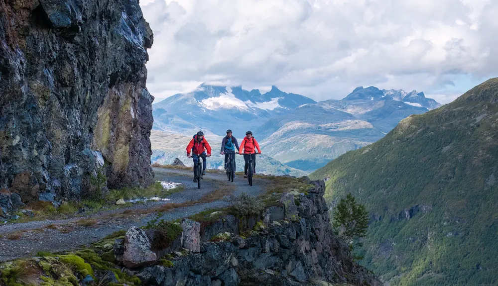 Syklister på Tusenmeteren med fjellene i Hurrungane som bakteppe