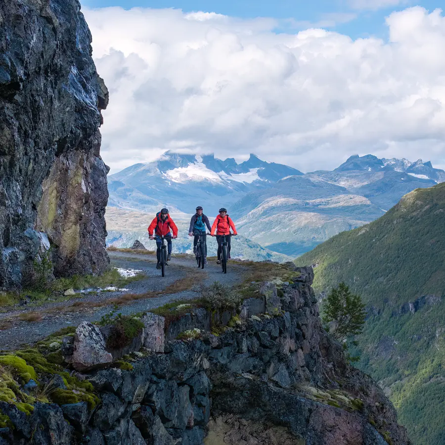 Syklister på Tusenmeteren med fjellene i Hurrungane som bakteppe