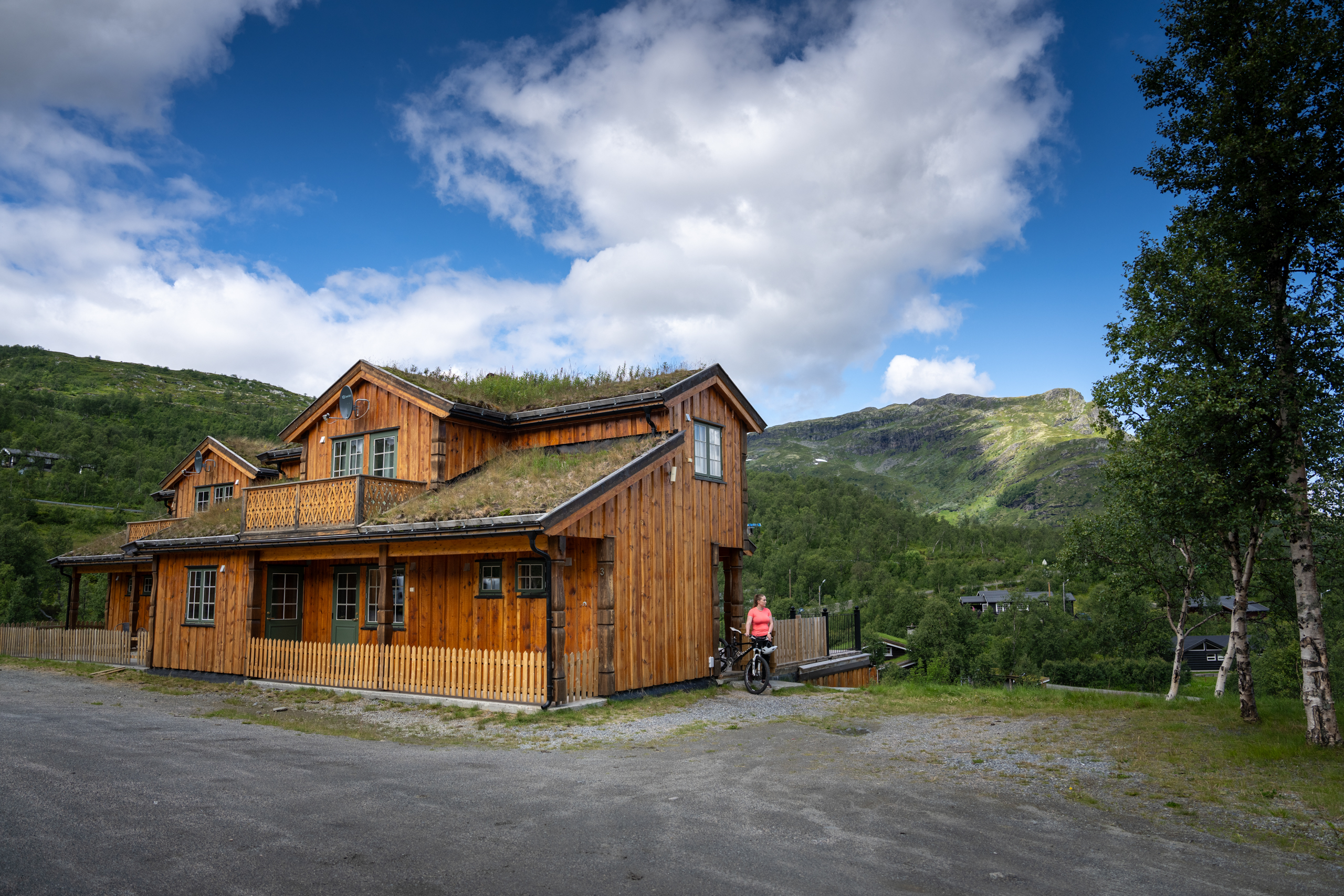 Kvinne kommer ut av leilighetene på Filefjellstuene med sykkel