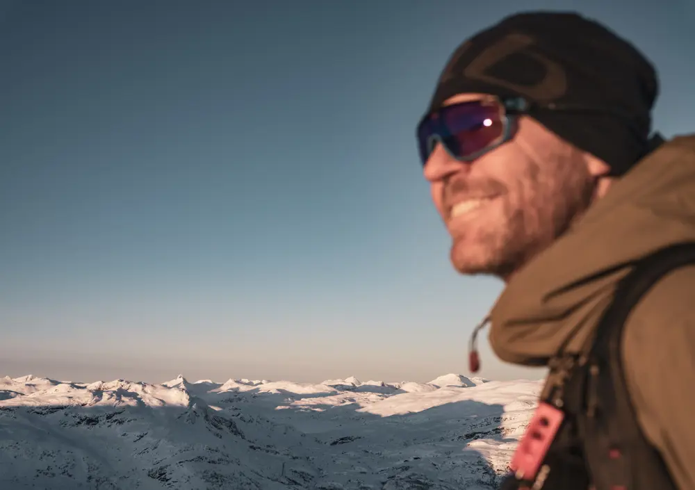 Smilende skikjører i vintersol på Tyin Filefjell med utsikt mot Jotunheimen