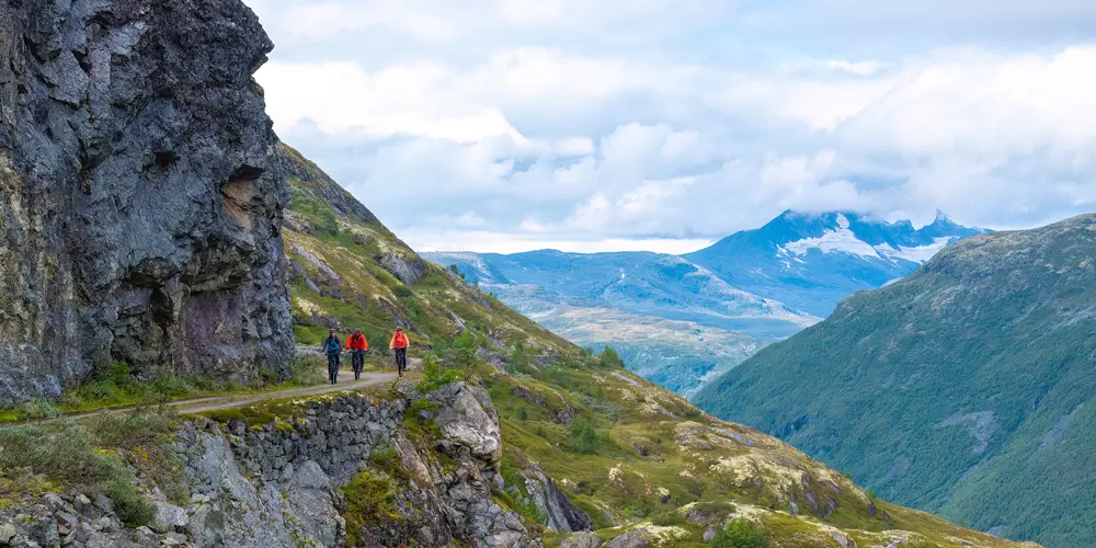 Syklister på Tusenmeteren med fjellene i Hurrungane som bakteppe
