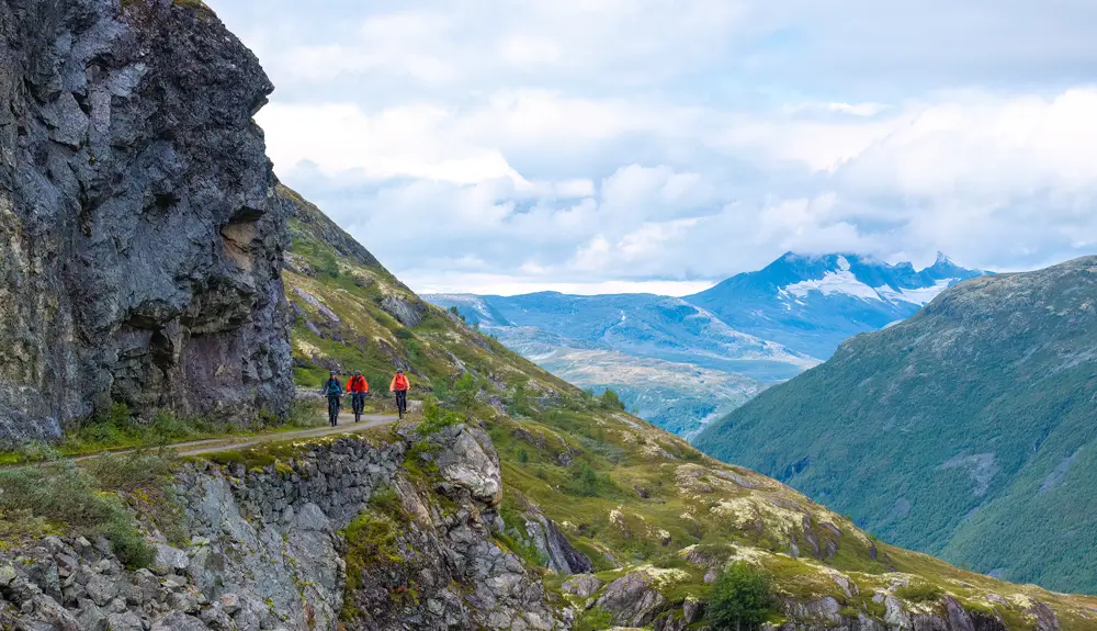 Syklister på Tusenmeteren med fjellene i Hurrungane som bakteppe