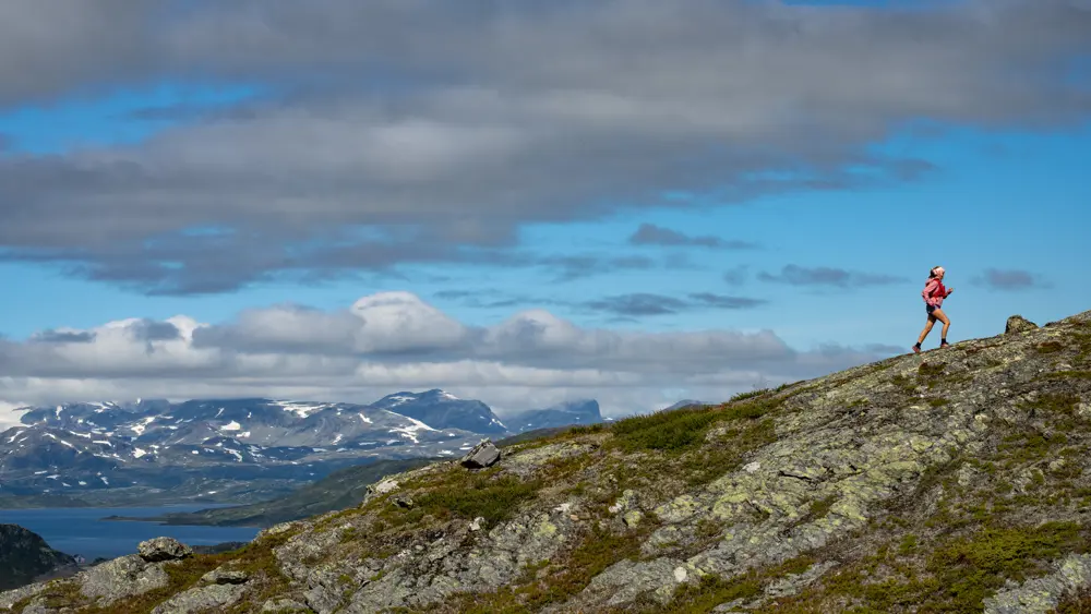 Trailrunner i høyfjellet – ung kvinne løper med Jotunheimen sine majestetiske fjell i bakgrunnen