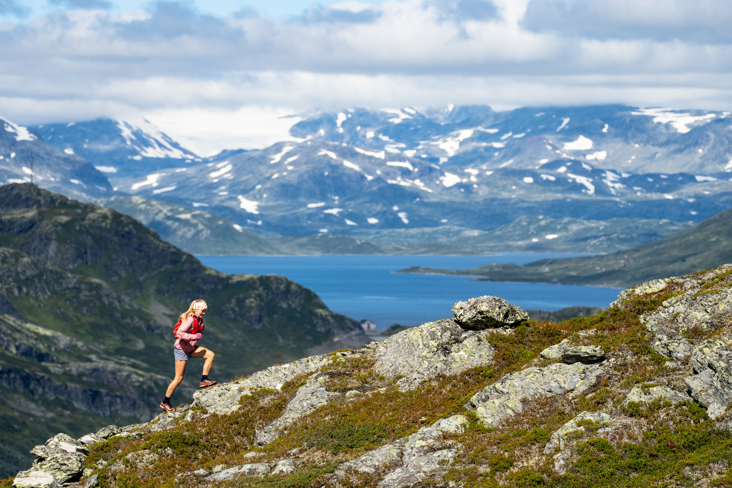 Trailrunner i høyfjellet – ung kvinne løper med Jotunheimen sine majestetiske fjell i bakgrunnen