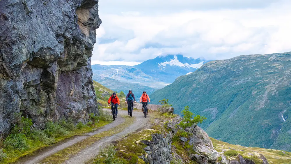 Syklister på Tusenmeteren med fjellene i Hurrungane som bakteppe